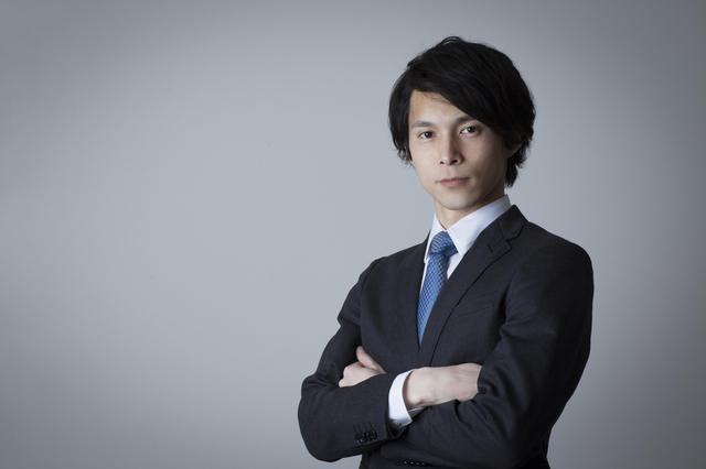 腕を組んでいるスーツ姿の男性